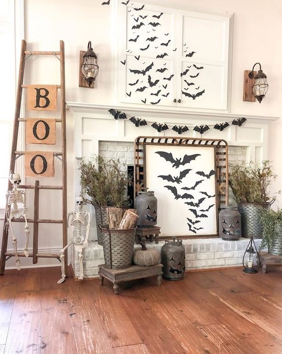 A rustic Halloween mantel with lots of bats, dried branches, jack o lanterns, skeletons, a ladder with letters