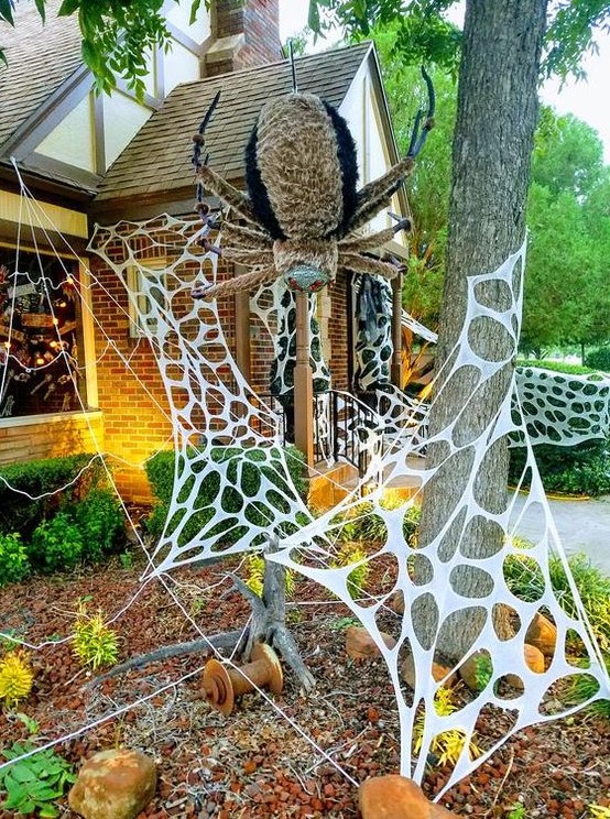 faux spiderweb and an oversized and scary spider are amazing to style your outdoors or front porch for Halloween and are cool