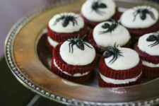 47 red velvet mini cakes with frosting and black chocolate spiders on top will be amazing wedding desserts or favors for a Halloween party