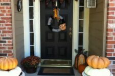 48 a simple Halloween porch styled with blooms and pumpkins plus a black and orange printed bunting is a very easy idea