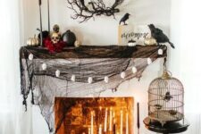 49 a stylish Halloween mantel with black spiderweb, lots of candles, skulls and black and gilded pumpkins plus blackbirds