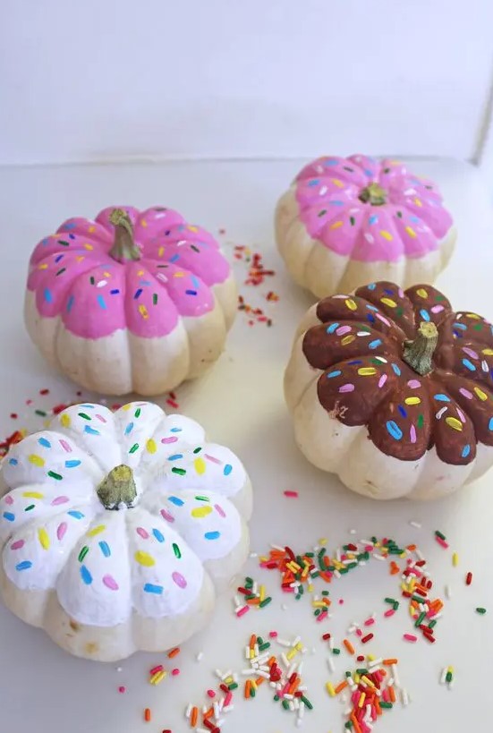 colorful pumpkins painted as glazed donuts with sprinkles for a fun and quirky touch