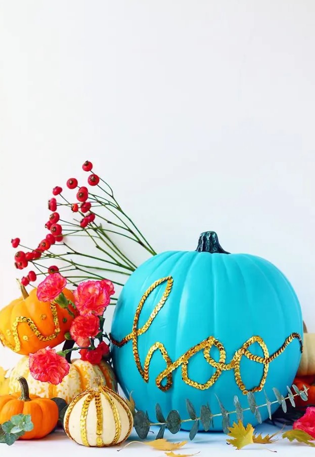 a bold blue pumpkin decorated with gold sequins that form a word is a cool and bright idea for Halloween