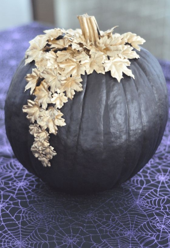 a shiny black pumpkin decorated with gold leaves on top is a chic and beautiful solution that feels like Halloween