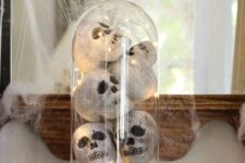 Halloween decor with books, a cloche with faux skulls and lights and spiderweb and a spider is easy to make