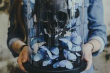a Halloween cloche with a black human skull and blue butterflies is amazing for party decor