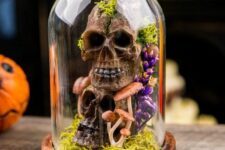 a Halloween cloche with moss, faux skulls, mushrooms and bold blooms is a cool and creative idea for decor