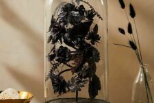 a Halloween decoration of a cloche with refined black blooms and leaves is a very sophisticated idea
