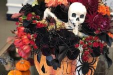 a Halloween decoration of a pumpkin, a spiderweb and a spider, bold red, orange and burgundy blooms, deep red callas and a skeleton