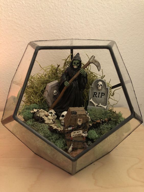 a Halloween terrarium with moss, a mini graveyard, skulls, Death and coffins is a cool and fun idea to realize