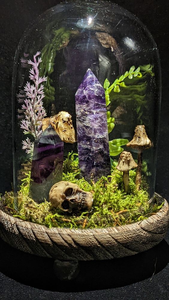 a Halloween terrarium with moss, mushrooms, a skull, some crystals and greenery is a catchy and bold decor idea