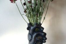 a black heart vase with deep red blooms on a stand is a bold and catchy idea for Halloween decor