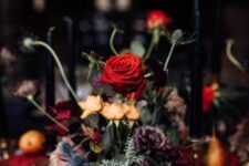 a bold Halloween centerpiece of orange, red and purple blooms, greenery and thistles is a catchy arrangement