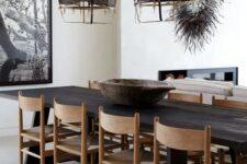 a bold and catchy dining space with a dark-stained dining table, light-stained chairs, dark pendant lamps and a bold artwork