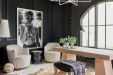 a bold soot home office with trim on the walls, a light-stained desk, a stool, creamy chairs and cowhide rugs