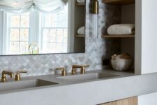 a chic bathroom with scallop tiles, a built-in fluted vanity, niche shelves, a large mirror and elegant brass sconces