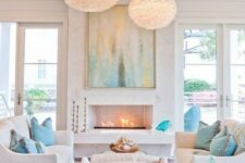 a chic white beach living room with aqua and turquoise touches, fluffy pendant lamps, a fireplace