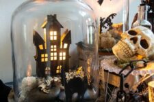a cloche with a haunted house, a black cat, some rocks and moss is a cool idea for Halloween decor