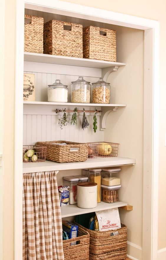a cozy and smart pantry with open shelves, baskets, metal wire baskets, containers for storage and a curtain is a smart idea