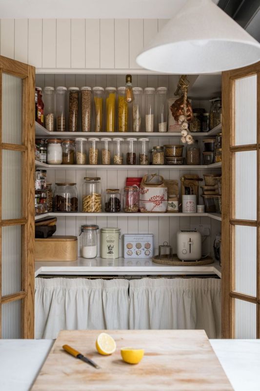 a cozy cottage pantry with open shelves, some storage hidden, jars and containers for food and cookware