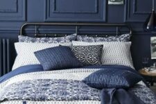 a dark blue wall with wainscoting and matching pillows for a relaxing moody space