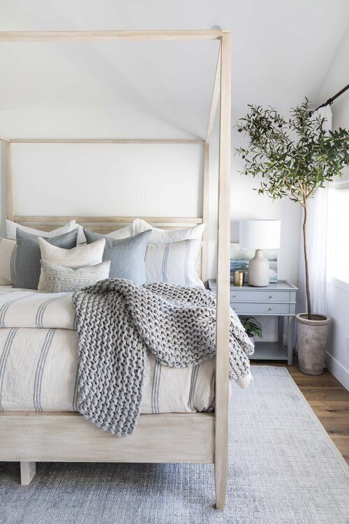 a delicate bedroom with a frame bed, blue and white bedding, a pastel blue rug and a pastel blue nightstand