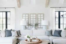 a farmhouse living room with a neutral sectional, pale blue chairs and printed pillows, a tiered coffee table