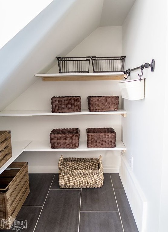 A farmhouse staircase pantry with built in shelves, railing with a hanging cubby, wooden boxes, wire and usual baskets