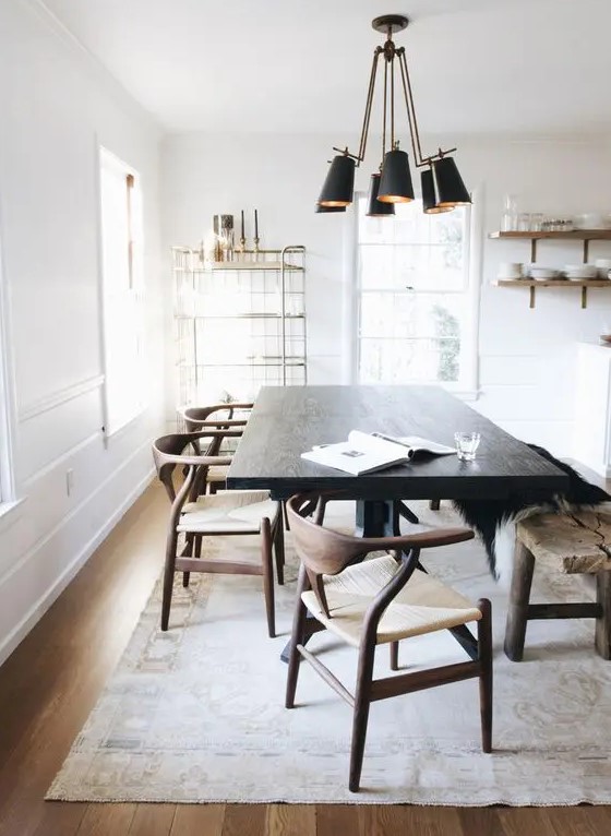 A light filled dining space with a very dark stained table that makes a statement, rich stained chairs and a light stained floor, a black pendant lamp and open shelves