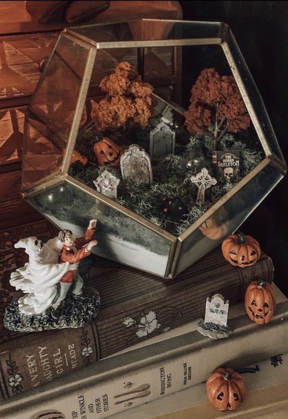A lovely Halloween terrarium with moss, tombstones, jack o lanterns, fall trees and a graveyard