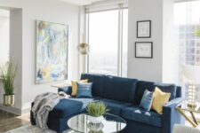a lovely modern living room with a navy sectional and printed pillows, a printed rug, an abstract artwork and neutral chairs
