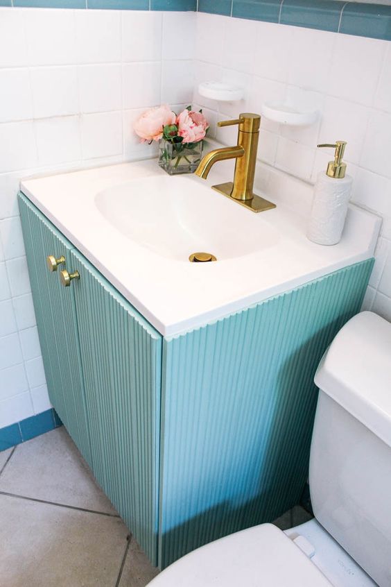 a lovely turquoise fluted vanity with a sink and a brass faucet is a cool soluton for a bold bathroom or powder room
