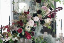 a lush and dimensional Halloween centerpiece of blush, mauve and fuchsia blooms, branches and greenery