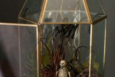 a mini Halloween terrarium with moss, fern, branches and twigs, a mini skeleton and a lotus slice is lovely