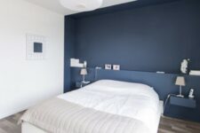 a cute minimalist bedroom with a navy accent wall