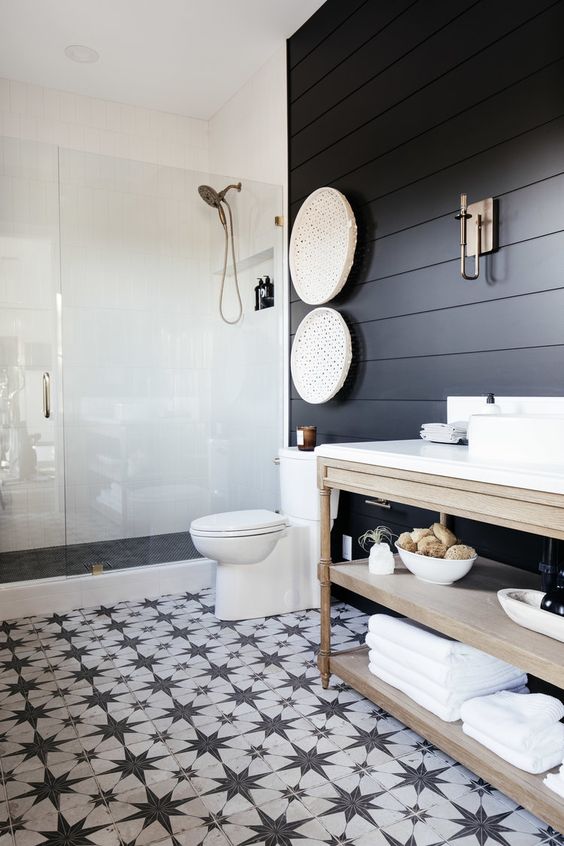 A modern farmhouse bedroom with soot shiplap walls, a shower space, a light stained vanity, a black and white star tile floor