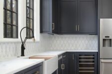 a modern farmhouse kitchen with soot cabinets, a white tile backsplash and white stone countertops, brass handles