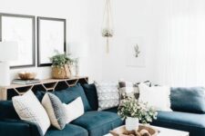 a modern farmhouse living room with a navy sectional, a sideboard, a coffee table, some art and potted blooms and greenery