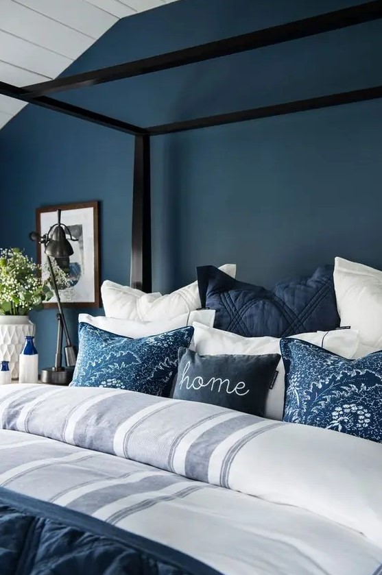 a navy statement wall plus navy pillows and a blanket contrast whites and make the space relaxing