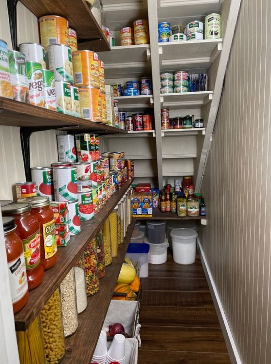A neutral farmhouse staircase pantry with open shelves, built in shelves in the stairs, plastic and metal containers