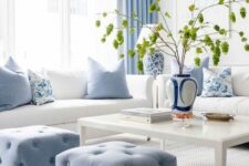 a pretty living room with white seating furniture, blue poufs and pillows, a low coffee table and blue curtains