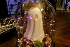 a simple Halloween cloche with moss, bold dried blooms, lights and a funky ghost figurine is a cool idea for a kids’ party