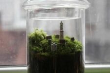 a simple and cool Halloween terrarium with pebbles, moss and a graveyard is a lovely idea to repeat for your space