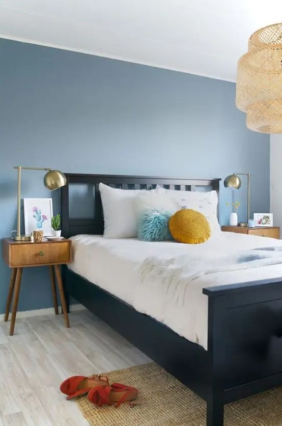 A slate blue accent wall and mustard touches add color to the mid century modern bedroom