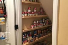 a small and cool under stairs pantry with ledges and shelves that allow storing canned food is a very practical solution