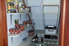a small and well-organized stairs pantry with open shelves and a built-in storage unit, with food and drinks stored