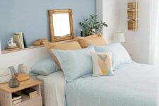a small bedroom with a blue accent wall, a bed with aqua and white bedding, a pastel nightstand and wooden touches