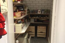 a small farmhouse pantry with subway and printed tiles, an open shelving system, crates and plastic boxes