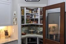 a small pantry with built-in corner storage units, with some appliances and jars and containers for food