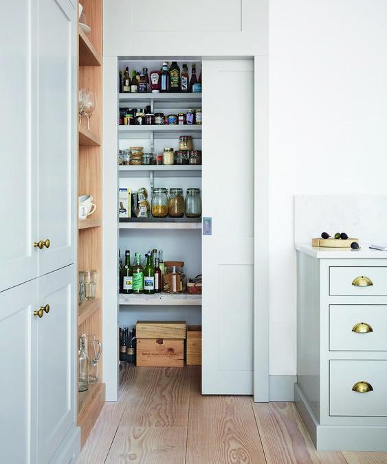 Kitchen with open door to the pantry larder cupboard, pale grey kitchen cupboards and wooden shelving.